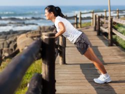 Frau macht am Strand positiven Liegestutz
