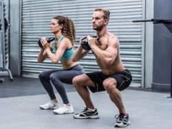 Muskulöses Paar macht Kniebeugen mit Kettlebell