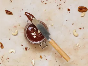 Nuss-Nougat-Creme Schokoaufstrich in einem Gläschen mit einem Messer oben aufgelegt