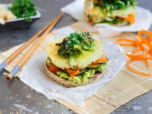 Burger mit Reisbratling und Algensalat auf einer Bambusmatte