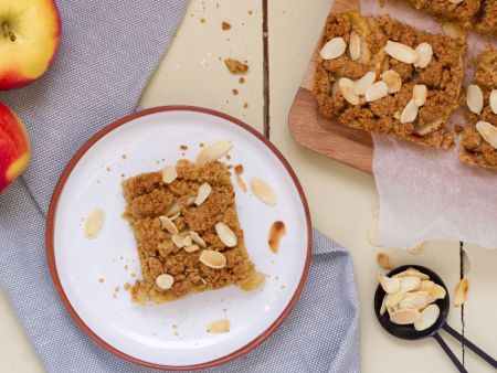 Apfelkuchen aus Mürbeteig Stück Blechkuchen auf hellem Teller, daneben weitere Kuchenstücke