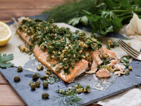 Lachs mit Kräuter-Walnuss-Salsa Angeschnittenes Lachsfilet mit Kräuter-Salsa, Kaper und Walnüsse auf Pergament