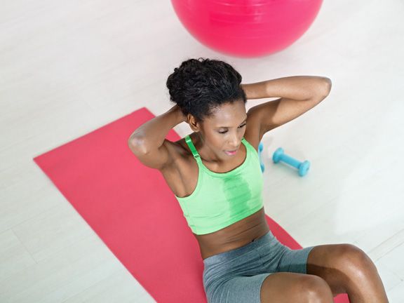 Dunkelhäutige Frau macht Crunches auf einer Fitnessmatte